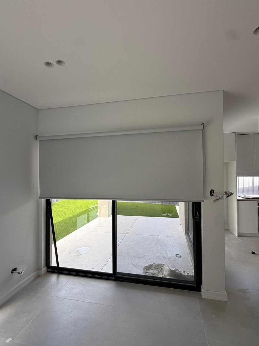 Blockout roller blind half lowered over a sliding door in a Perth home