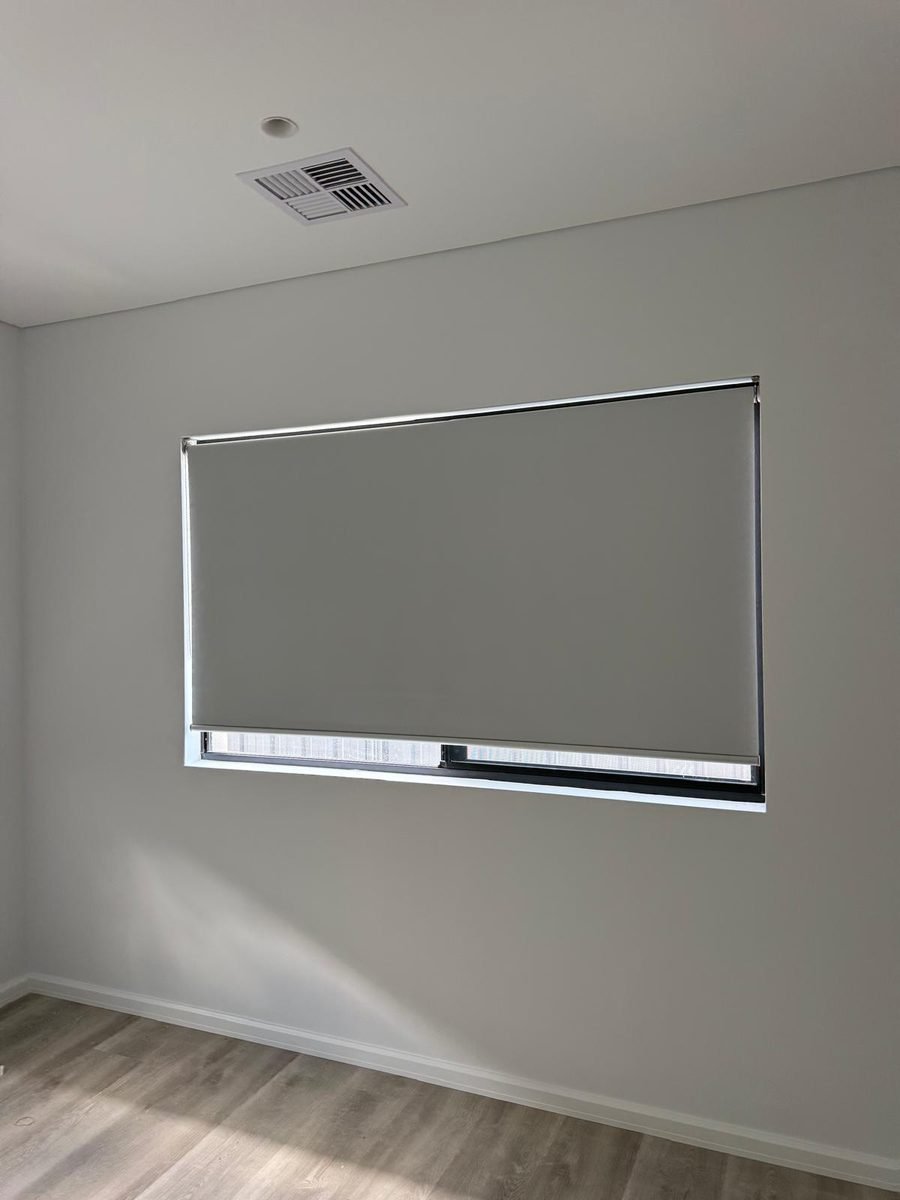 Wide grey roller blind covering a large living room window