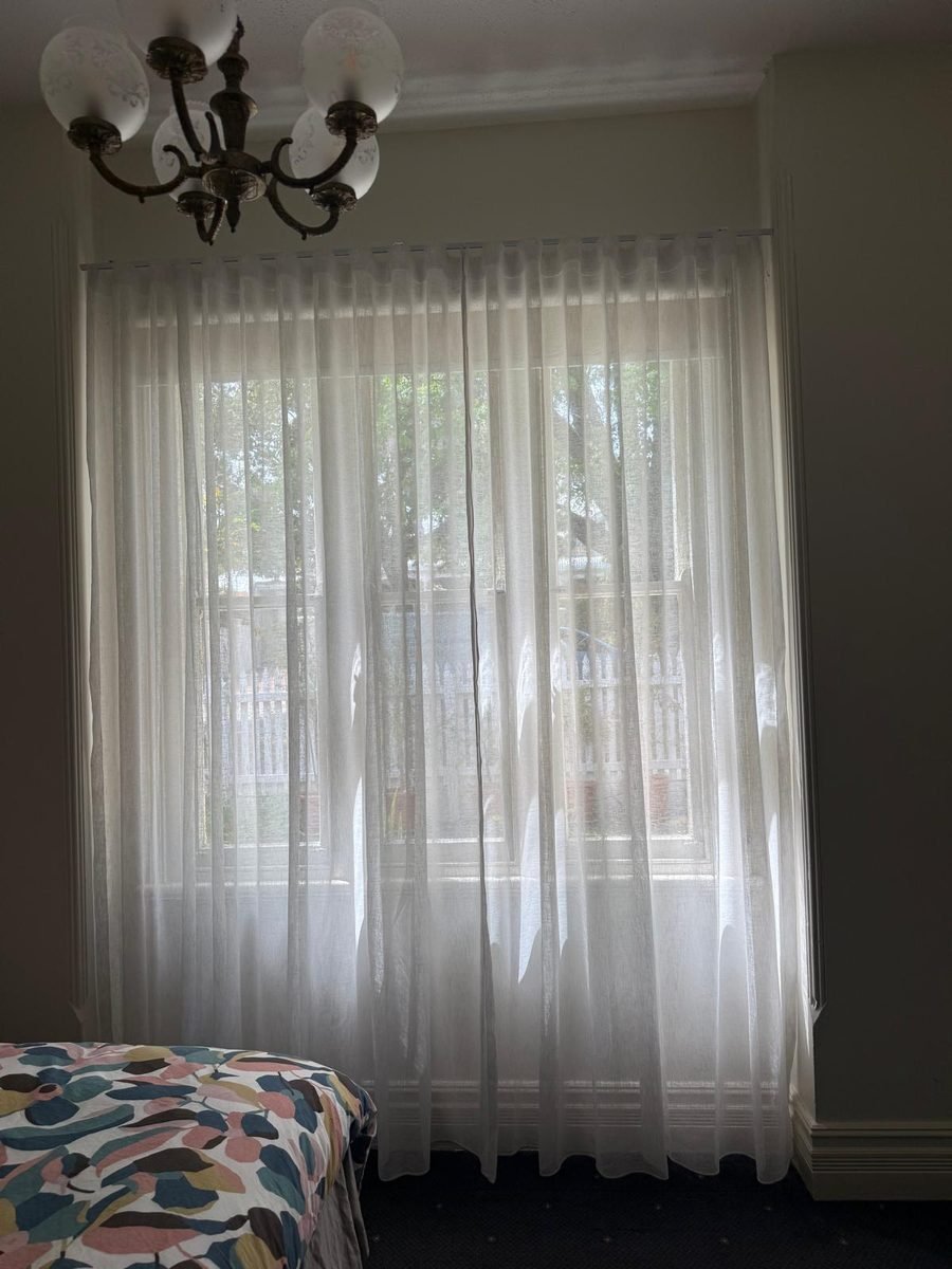 Floor length sheer curtains over a large bedroom window in a Perth home